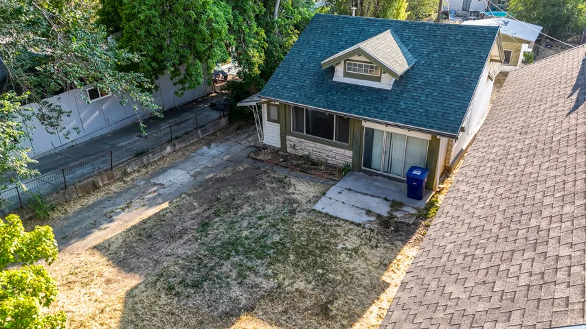 House featuring a dormer window, green shingle roof, sliding glass door, and an exterior patio