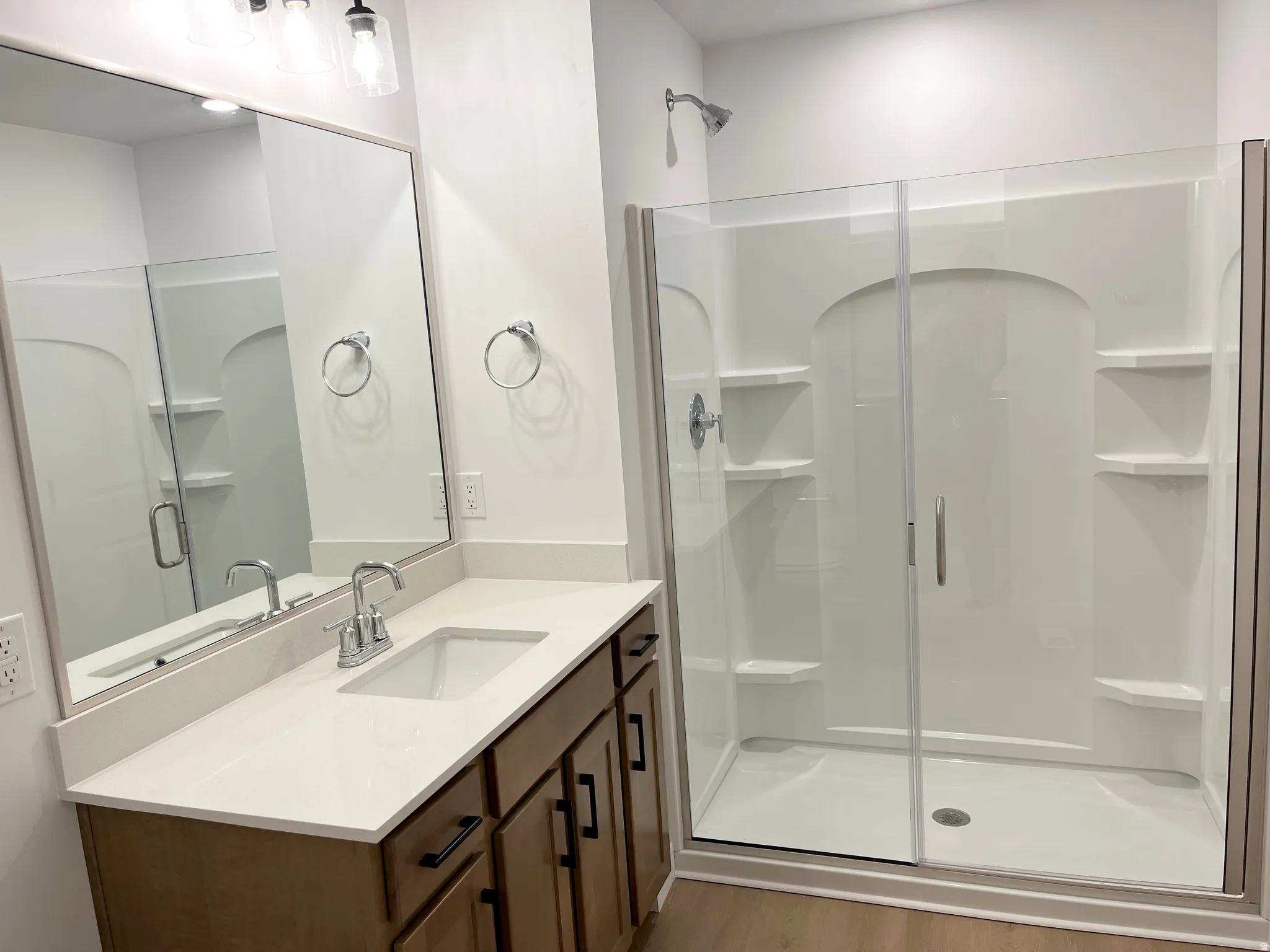 Vanity with an integrated sink, polished chrome faucet, wood-finish cabinetry, and quartz-finish countertop