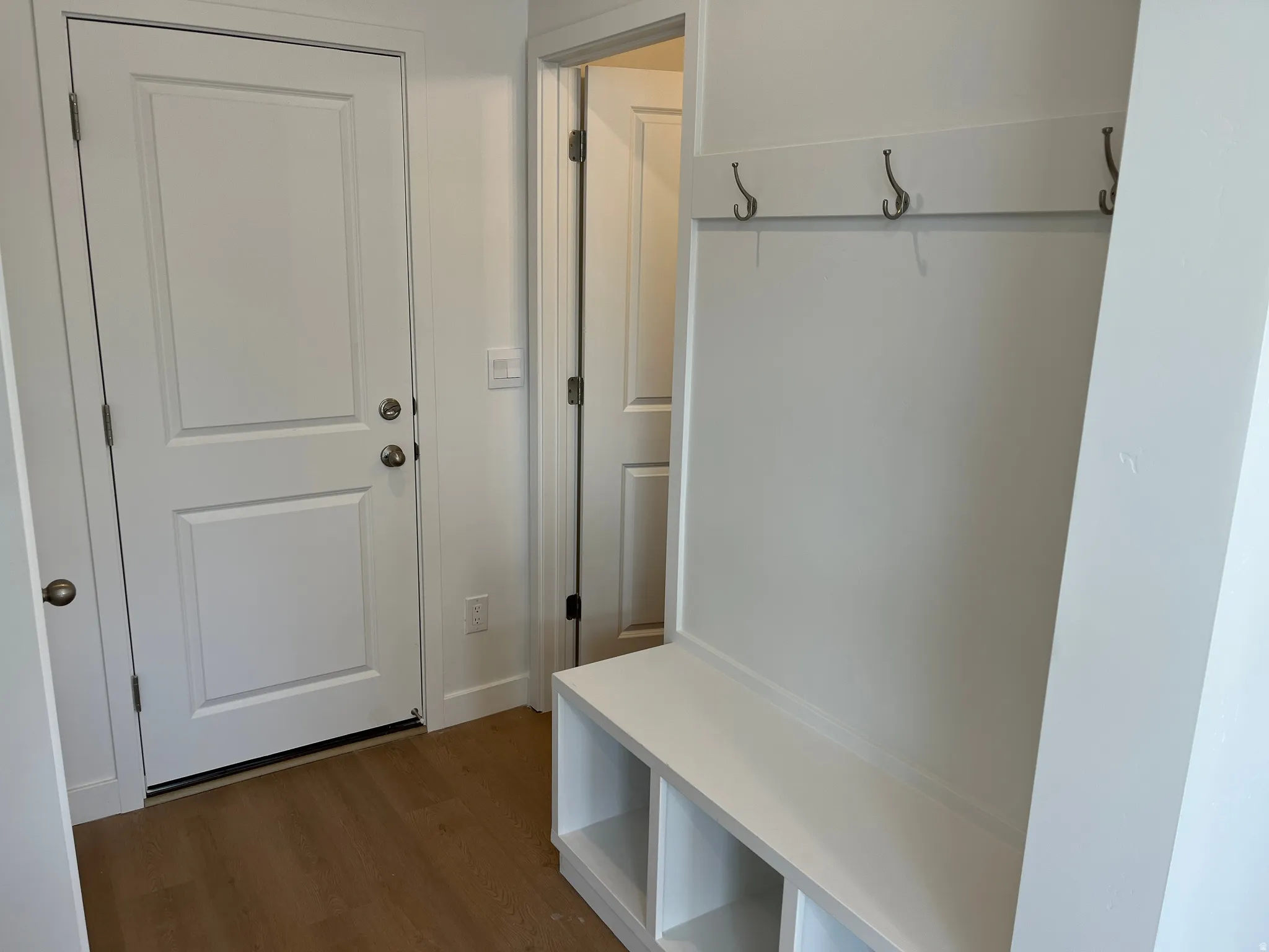 White paneled doors, light wood-finish flooring, and a built-in bench with storage cubbies