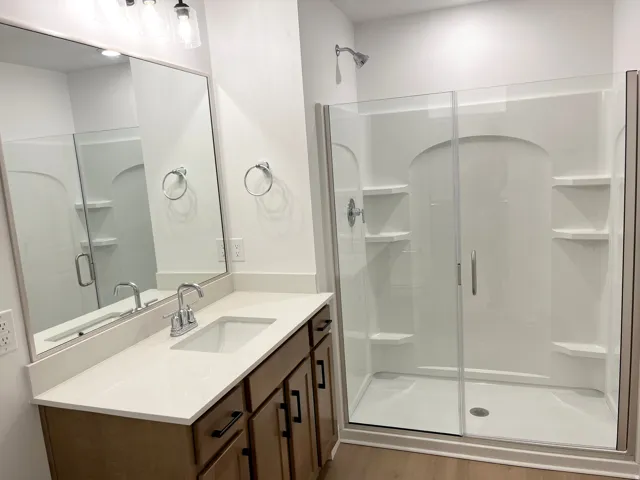 Vanity with an integrated sink, polished chrome faucet, wood-finish cabinetry, and quartz-finish countertop