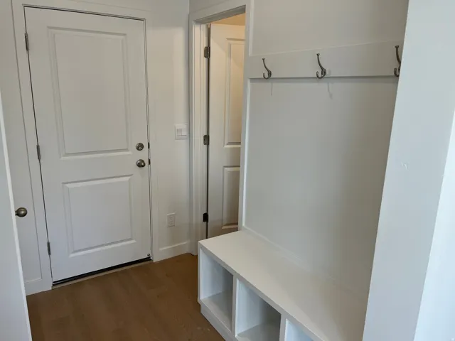 White paneled doors, light wood-finish flooring, and a built-in bench with storage cubbies