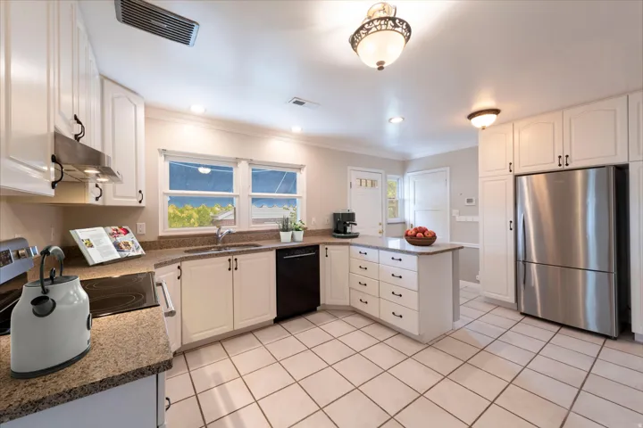White cabinetry, tile flooring, built-in appliances, recessed lighting, and a kitchen island