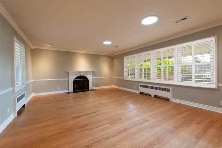 Hardwood flooring, decorative fireplace, extensive crown molding, transom windows with plantation shutters, and recessed lighting