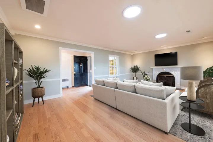 Hardwood flooring, crown molding, chair rail detailing, recessed lighting, and a prominent fireplace with an ornate mantel