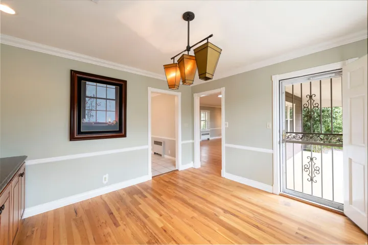 Hardwood flooring throughout, crown molding, chair rail detailing, recessed lighting, and a decorative security door