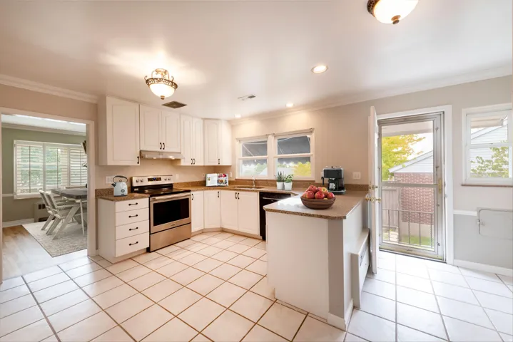 White cabinetry, stainless steel appliances, tile flooring, and a built-in kitchen island with a countertop