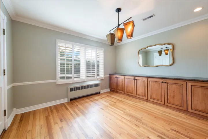 Hardwood flooring, crown molding, chair rail molding, built-in cabinetry with a countertop, and window shutters