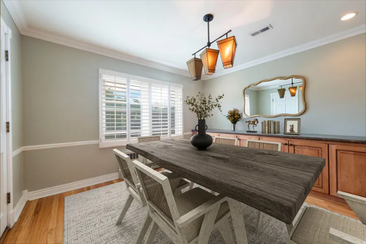 Hardwood flooring, built-in cabinetry with a countertop, crown molding, chair rail molding, and window shutters
