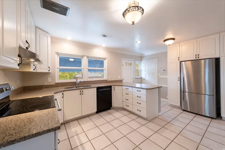 Kitchen featuring white cabinetry, granite-style countertops, stainless steel appliances, and a central island with storage drawers