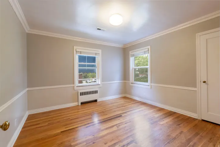 Hardwood flooring, painted walls with chair rail and crown molding, white trim windows, and a flush mount ceiling light