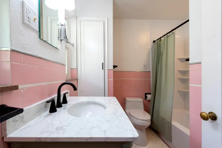 Vanity with an integrated sink and matte black faucet, surrounded by pink wall tile