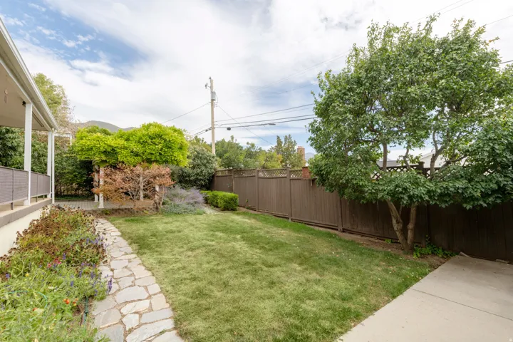 Expansive backyard with a manicured lawn, established landscaping, and a stone-paved pathway