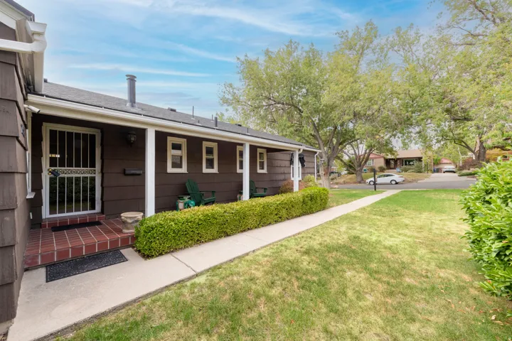 Covered front porch with white columns, brick entry, and security screen door