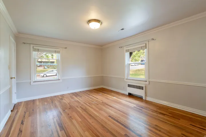 Hardwood-finish flooring, two windows, crown molding, chair rail molding, and a flush-mount ceiling light fixture
