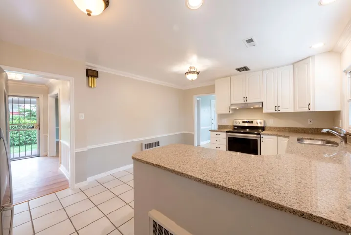 Kitchen featuring white cabinetry, stone-finish countertops, stainless steel appliances, and tile flooring