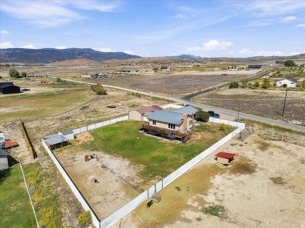Expansive lot featuring a residential structure with a metal roof, a wrap-around deck, and a fenced yard