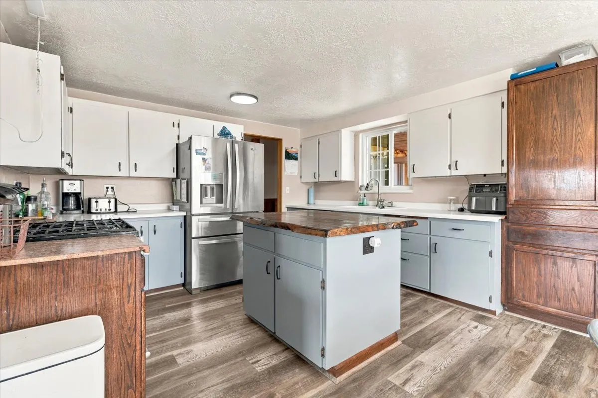 Kitchen featuring wood-finish flooring, two-tone cabinetry, and a central island with a wood countertop