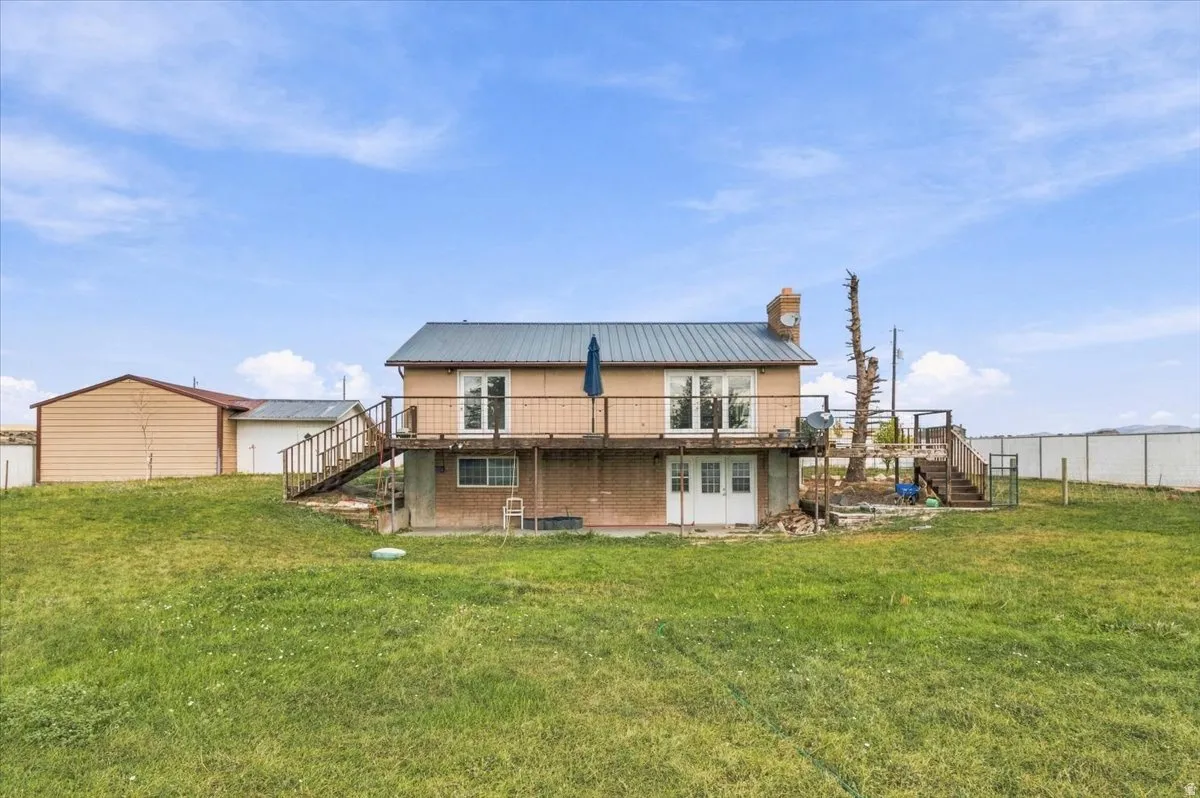 Two-story residence featuring a metal roof, an upper-level balcony, and a walk-out lower level