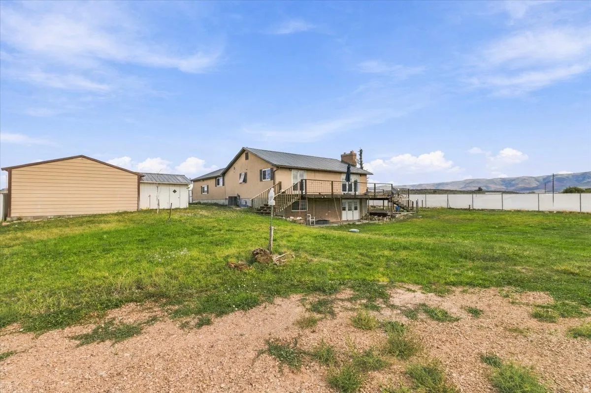 Expansive rear yard with a multi-level deck, detached storage shed, and a separate outbuilding