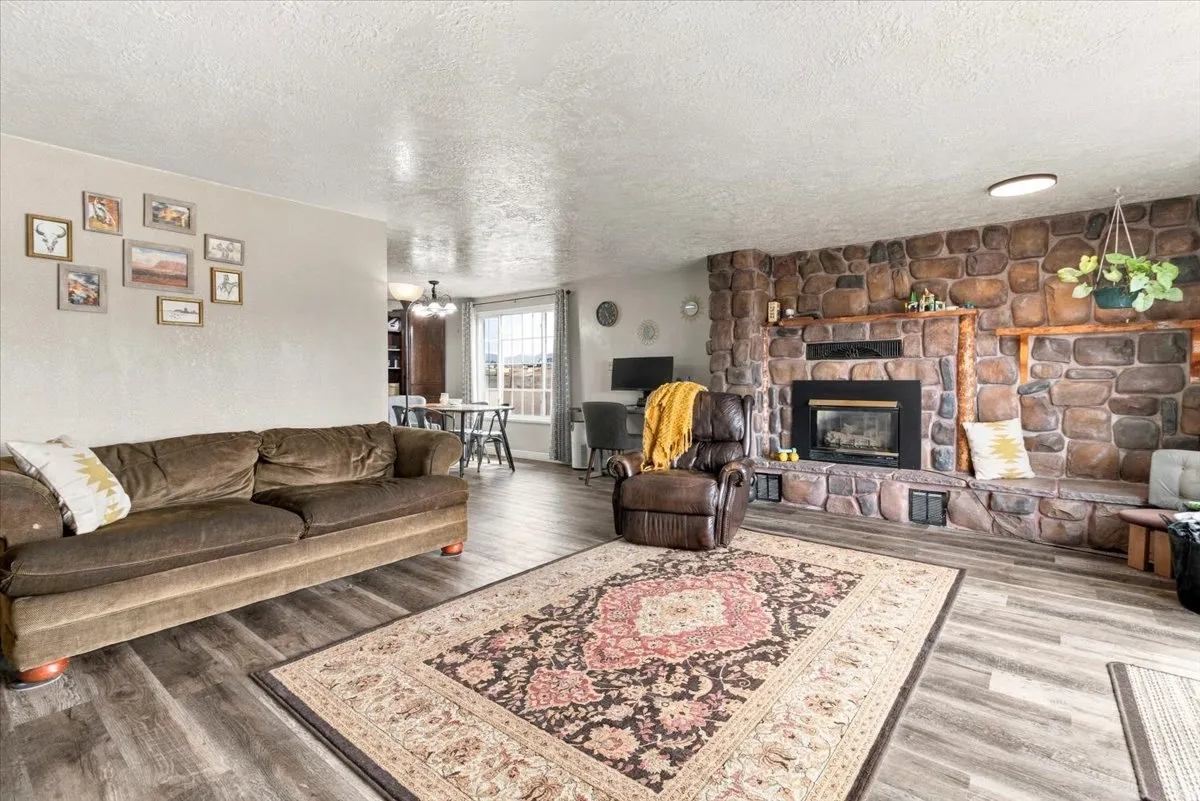 Stone-clad fireplace with a wood mantle, wood-finish flooring, and recessed lighting