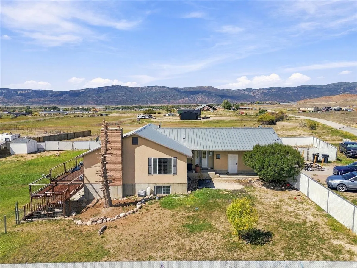 Stucco exterior with a metal roof, brick chimney, multi-level wood deck, and expansive surrounding landscape