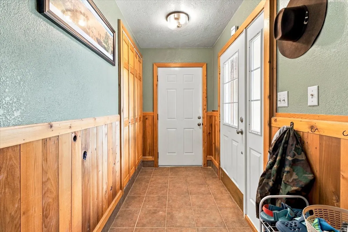 Tile flooring, vertical wood paneling, white interior doors with hardware, and overhead lighting