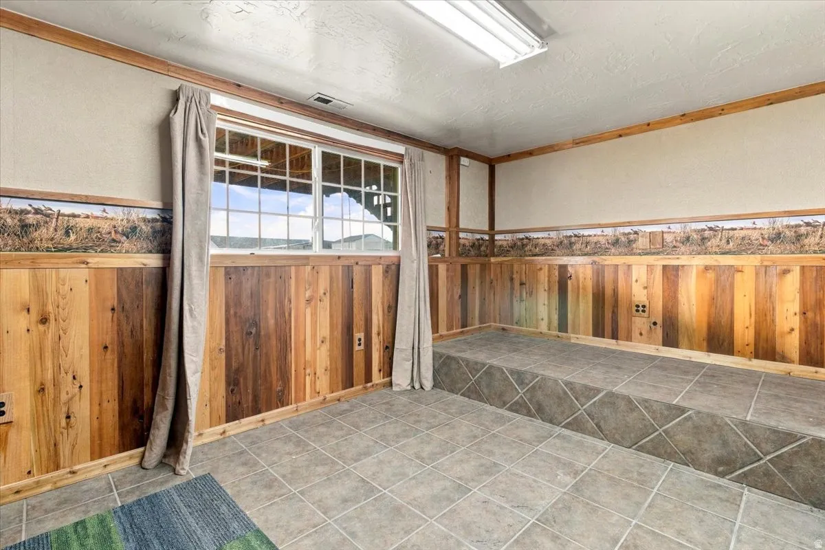 Window with grids, wood paneling, tiled flooring, tiled raised platform, and fluorescent overhead lighting