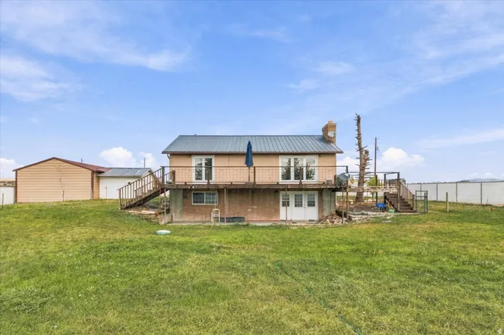Two-story residence featuring a metal roof, an upper-level balcony, and a walk-out lower level