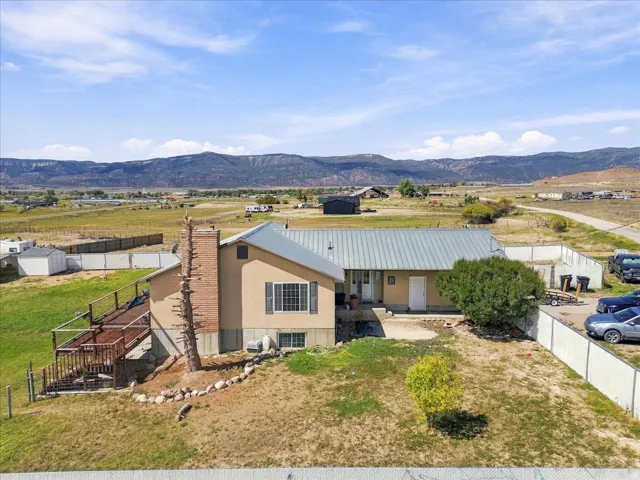 Stucco exterior with a metal roof, brick chimney, multi-level wood deck, and expansive surrounding landscape