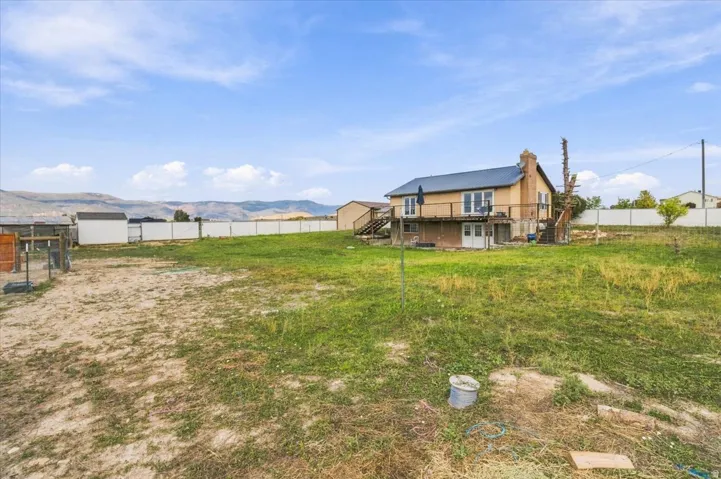 Expansive rear yard with a two-story residence featuring a metal roof, an upper-level deck, and a walk-out lower level
