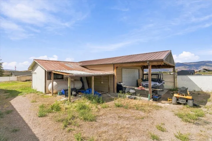 Detached outbuilding with a metal roof, covered carport, and covered porch area