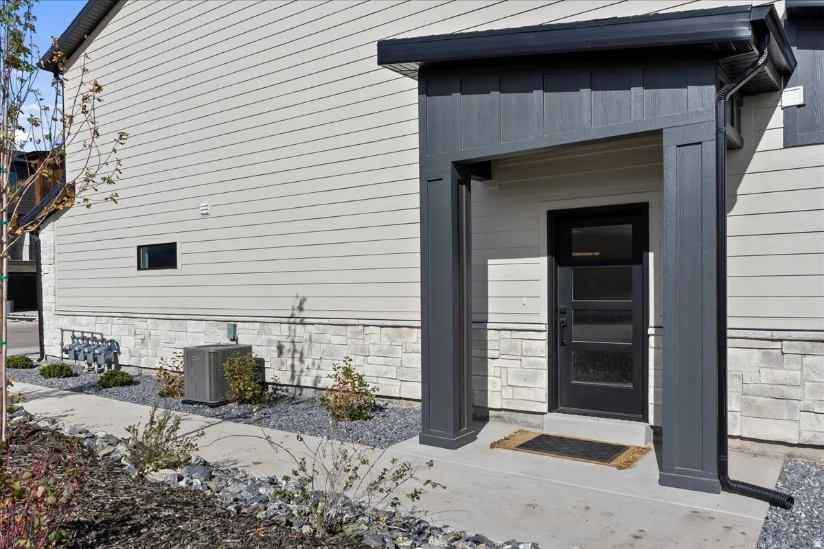 Contemporary exterior with vertical paneling accent, light-toned siding, and a stone veneer foundation