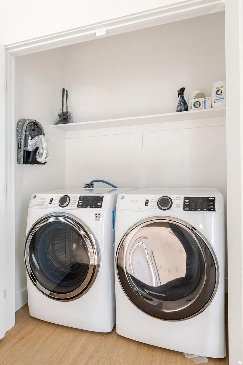 Dedicated laundry closet with wood-finish flooring and a built-in storage shelf