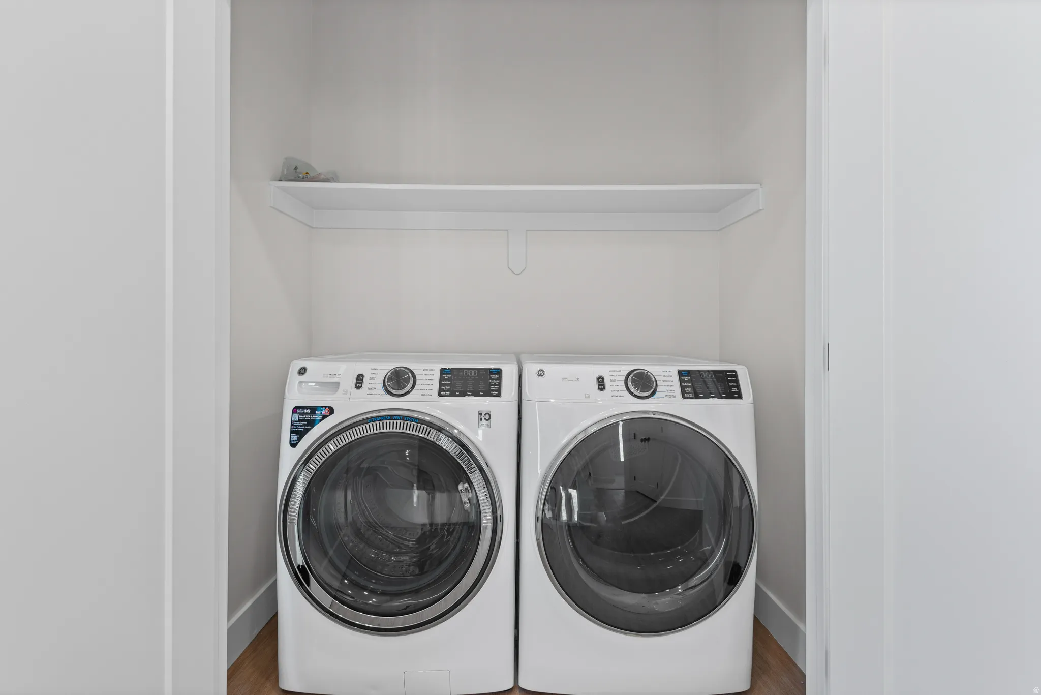 Laundry area with a built-in shelf and wood-finish flooring