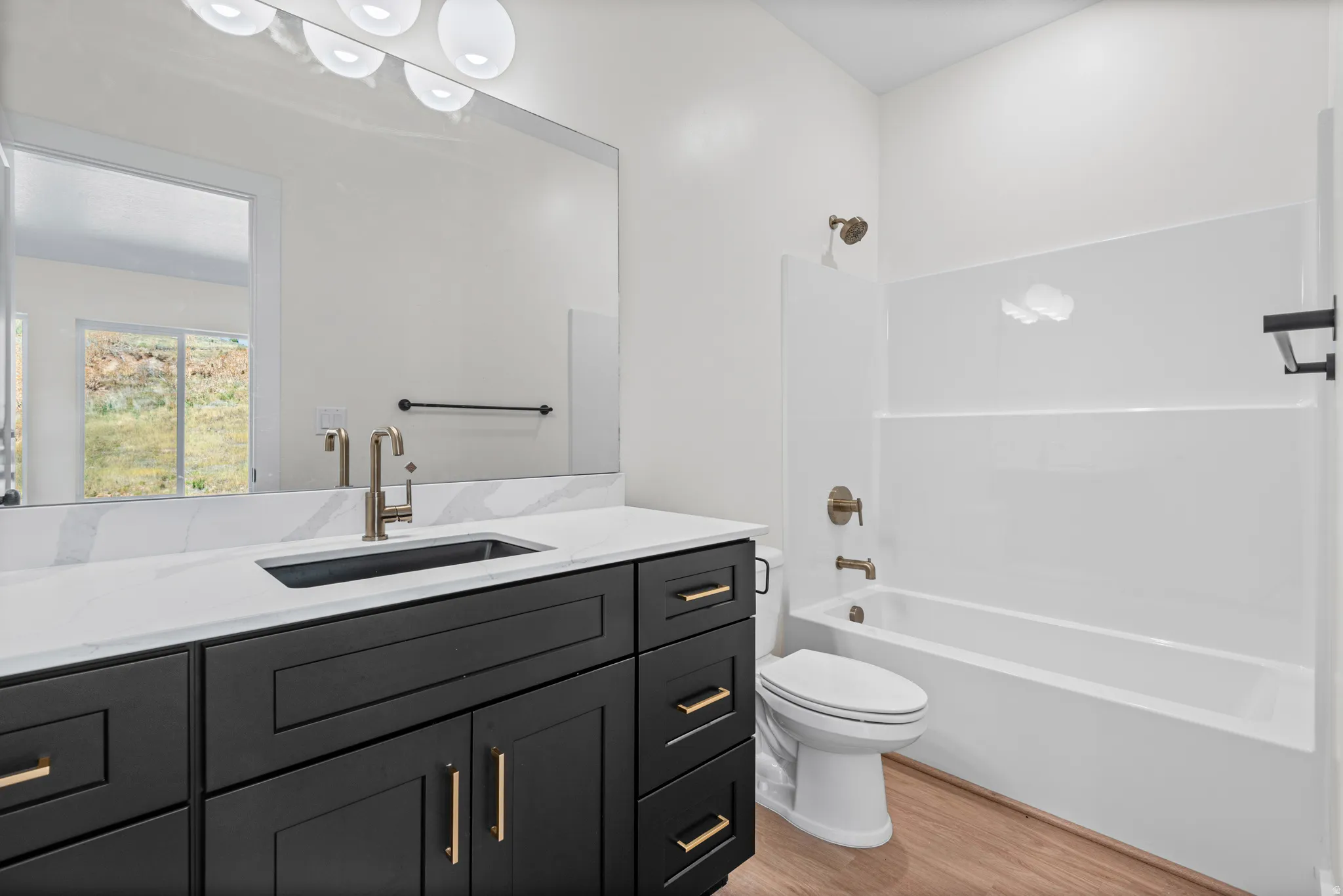 Dark wood-finish vanity with gold-tone hardware, rectangular undermount sink, white countertop, and contemporary faucet