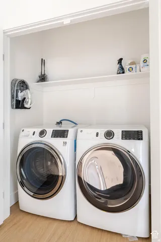 Dedicated laundry closet with wood-finish flooring and a built-in storage shelf