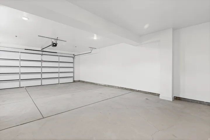 Spacious garage with a concrete floor, overhead door, and white painted walls