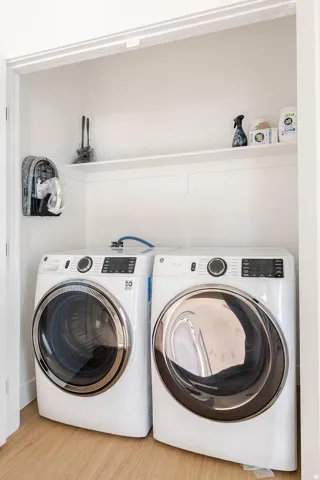 Dedicated laundry closet with wood-finish flooring and a built-in storage shelf