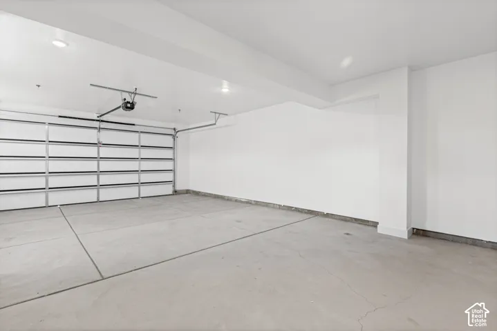 Spacious garage with a concrete floor, overhead door, and white painted walls