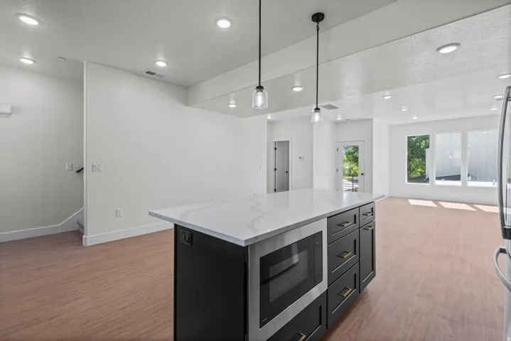 Modern kitchen island with a light-toned countertop, integrated microwave, and dark cabinetry