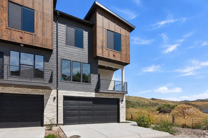 Contemporary exterior with dark siding, stone veneer accents, and wood-finish paneling