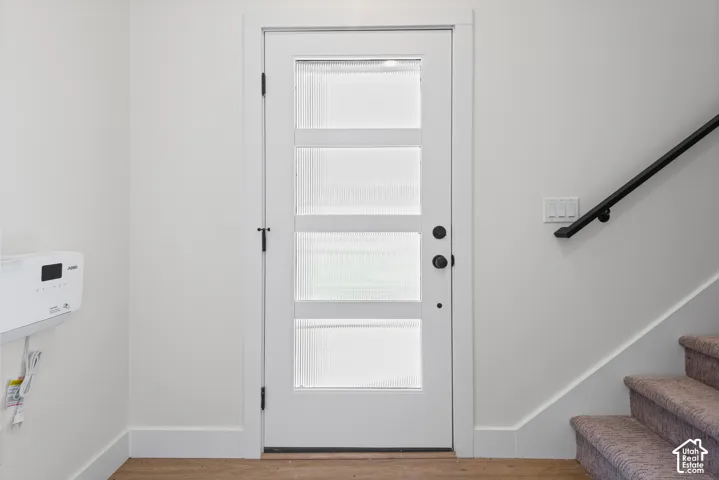 White interior door with four frosted glass panels and matte black hardware, accompanied by a black wall-mounted handrail and a carpeted staircase