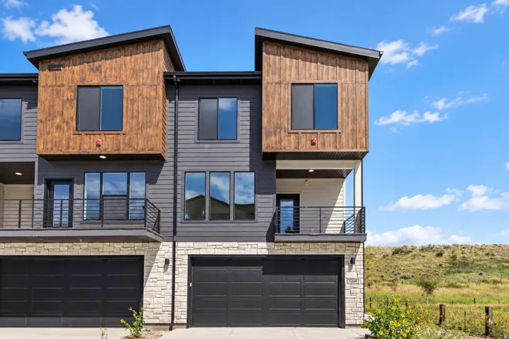 Contemporary facade featuring dark gray siding, wood-finish accent panels, and stone veneer