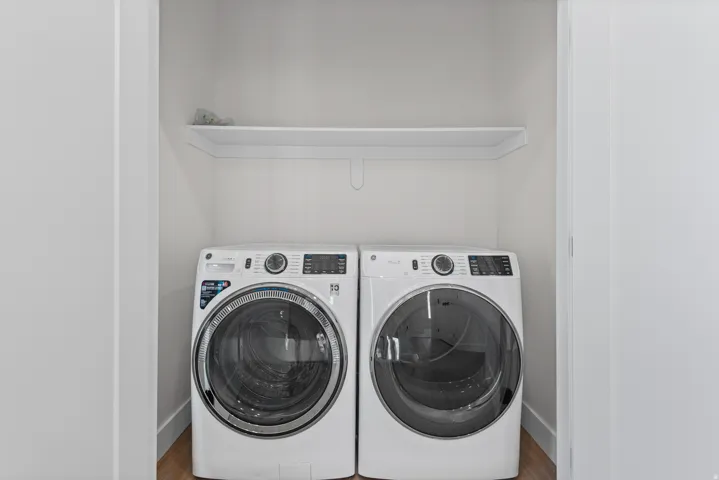 Laundry area with a built-in shelf and wood-finish flooring
