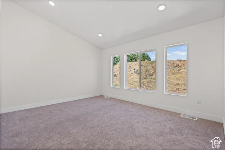 Vaulted ceiling with recessed lighting, three large windows, and neutral carpeting