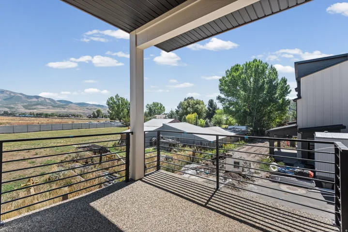 Balcony featuring a speckled concrete surface, black horizontal railing, and an overhead support column