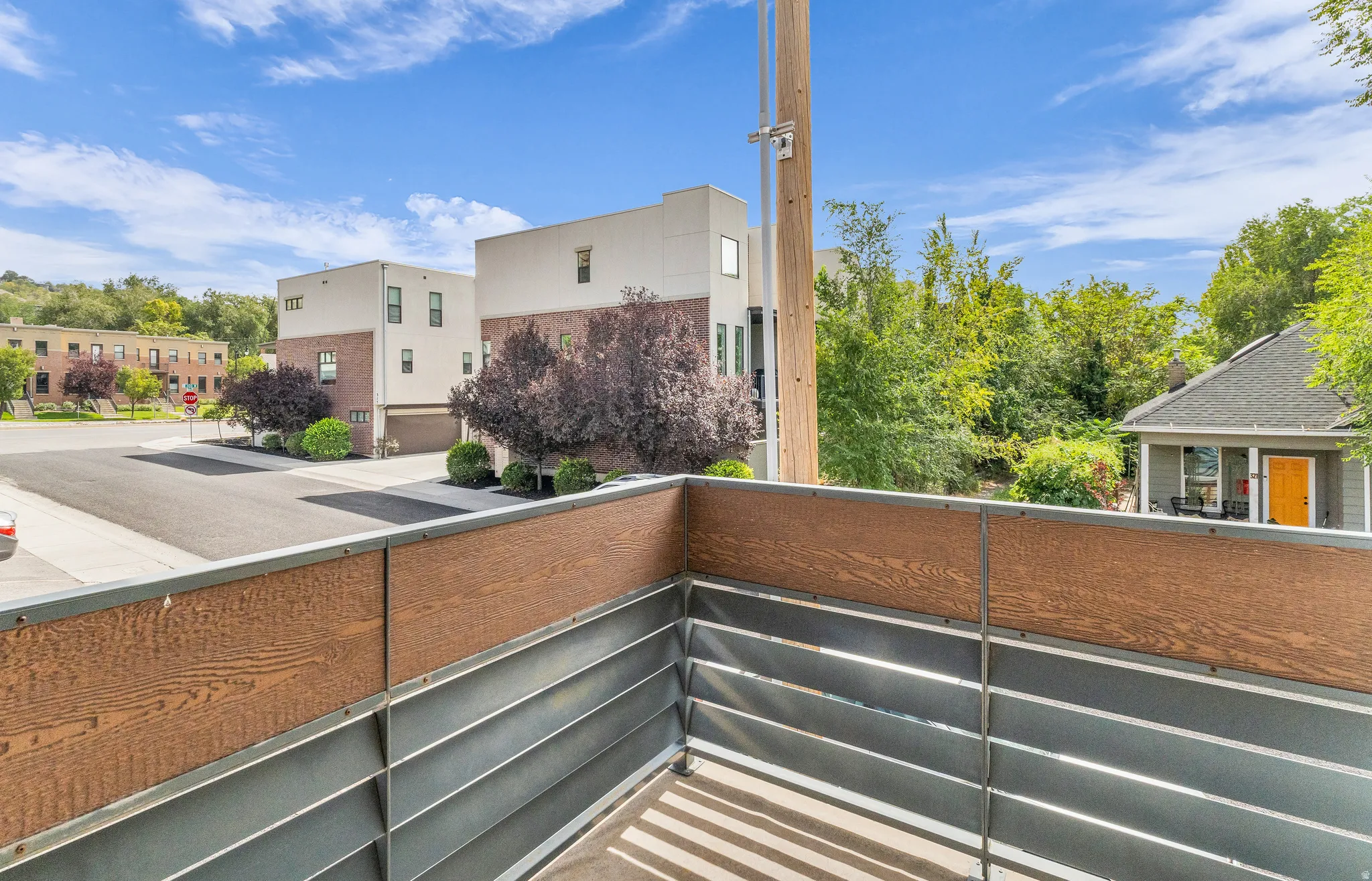 Private balcony  off of Primary bedroom with horizontal metal and wood-finish paneling, offering neighborhood views