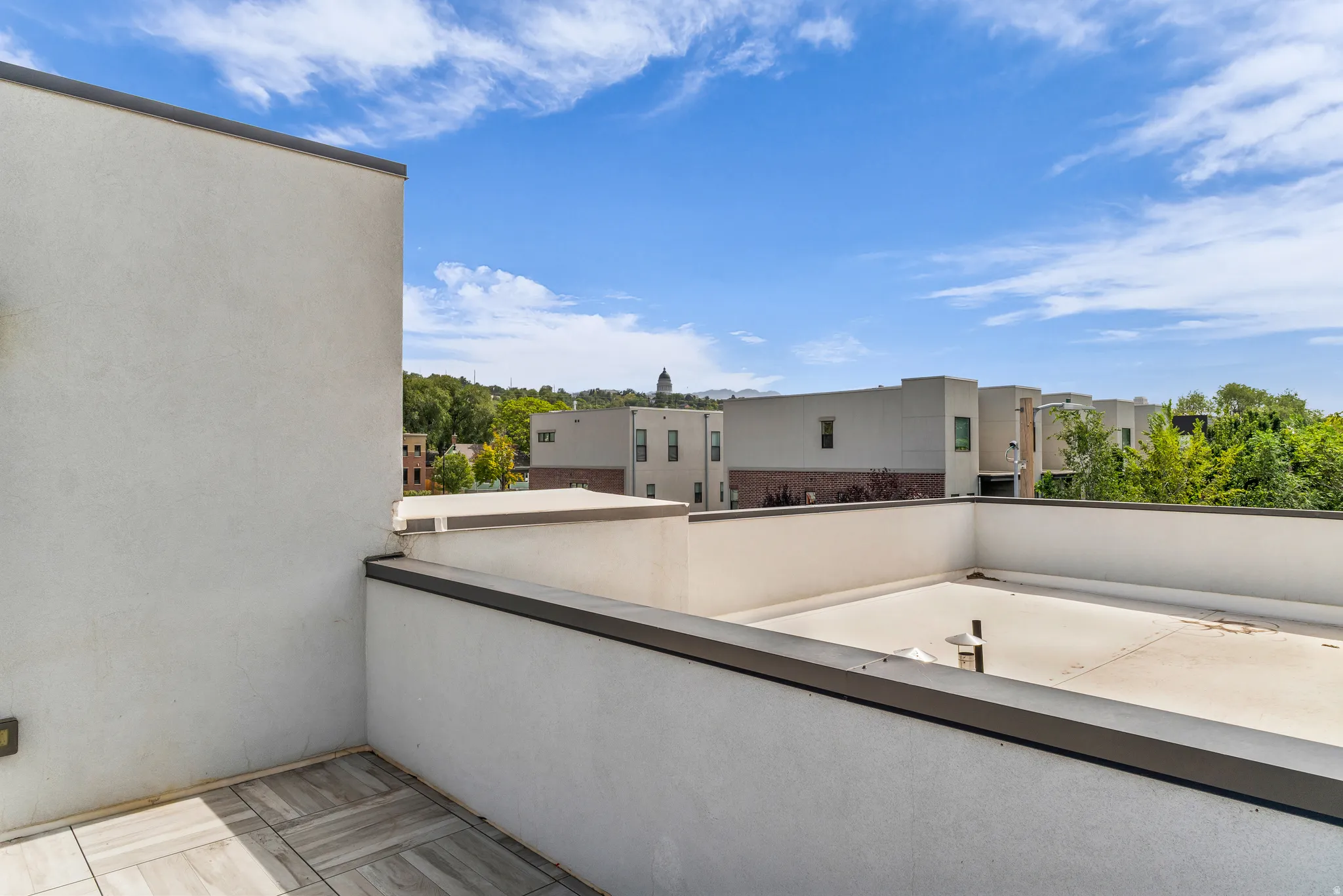 Rooftop patio with tiled flooring and low stucco walls