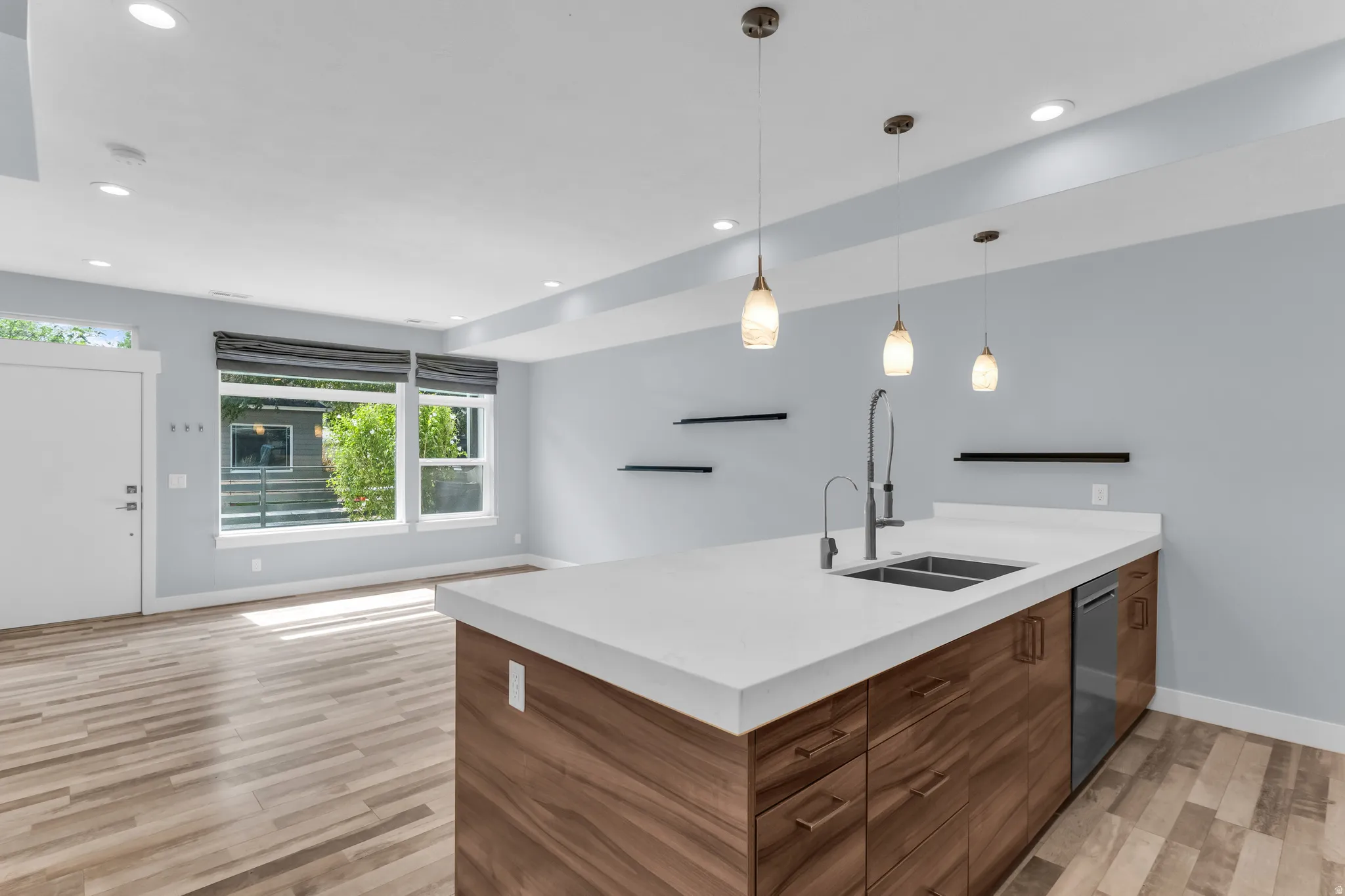 Spacious open-concept living area featuring wood-finish flooring, recessed lighting, and large windows