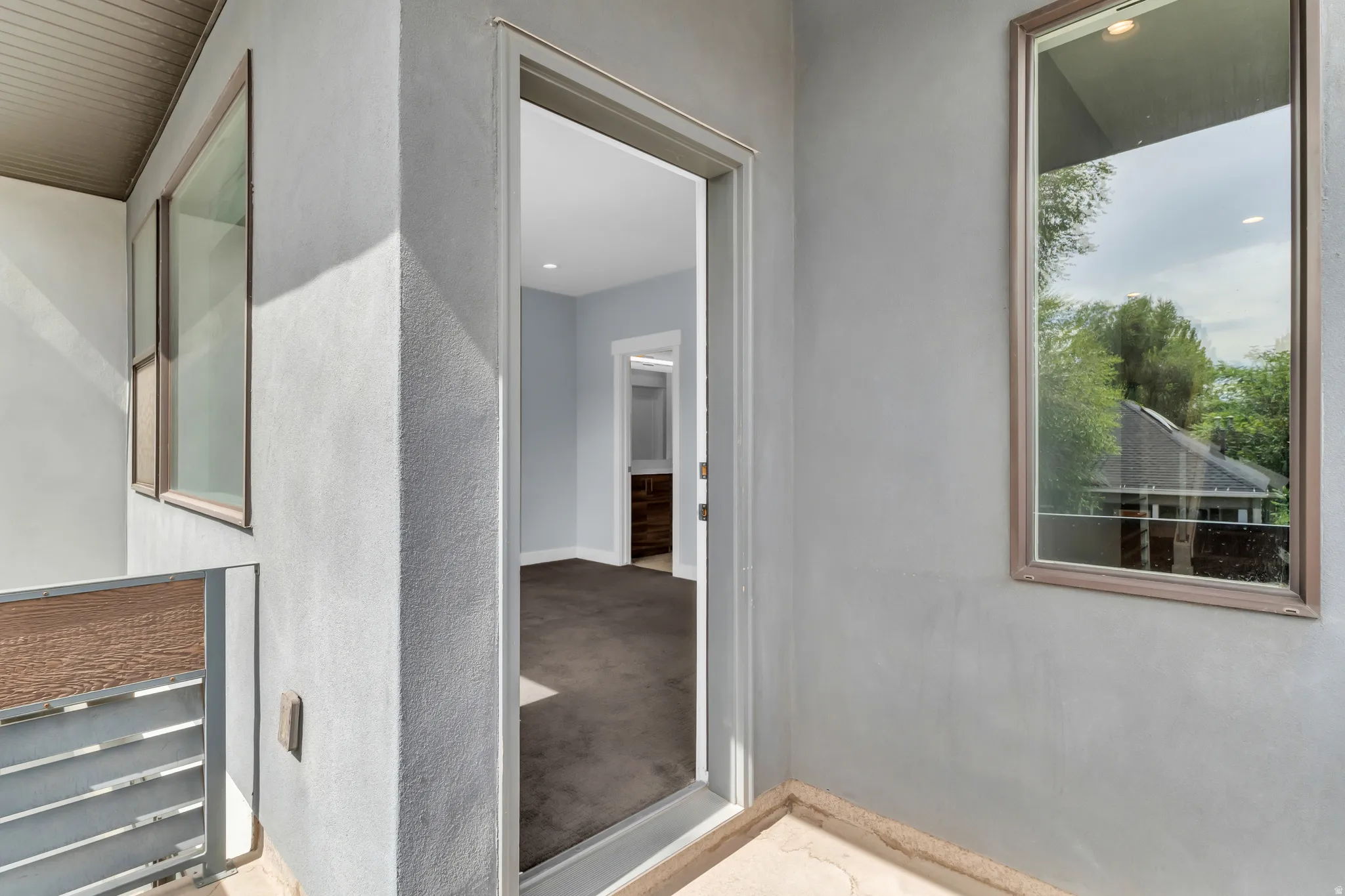 Stucco exterior with multiple windows and a metal railing